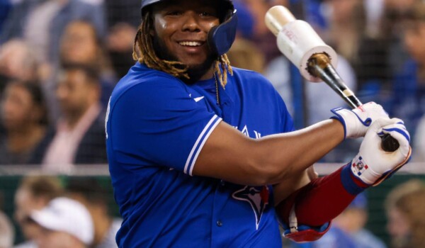 A man in a blue baseball uniform swinging a bat.