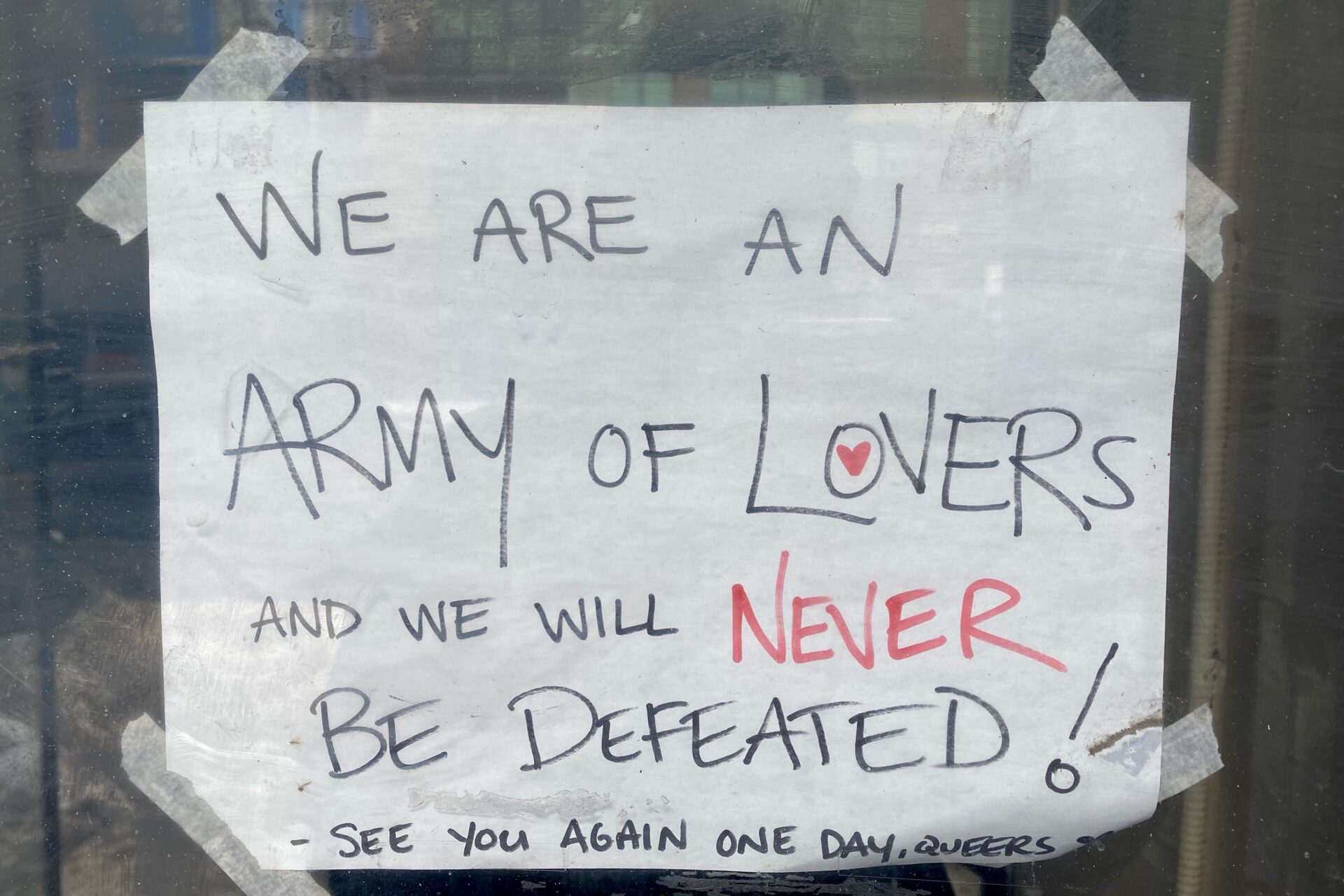 A hand-written sign that says "We are an ARMY of LOVERS and we will NEVER BE DEFEATED"