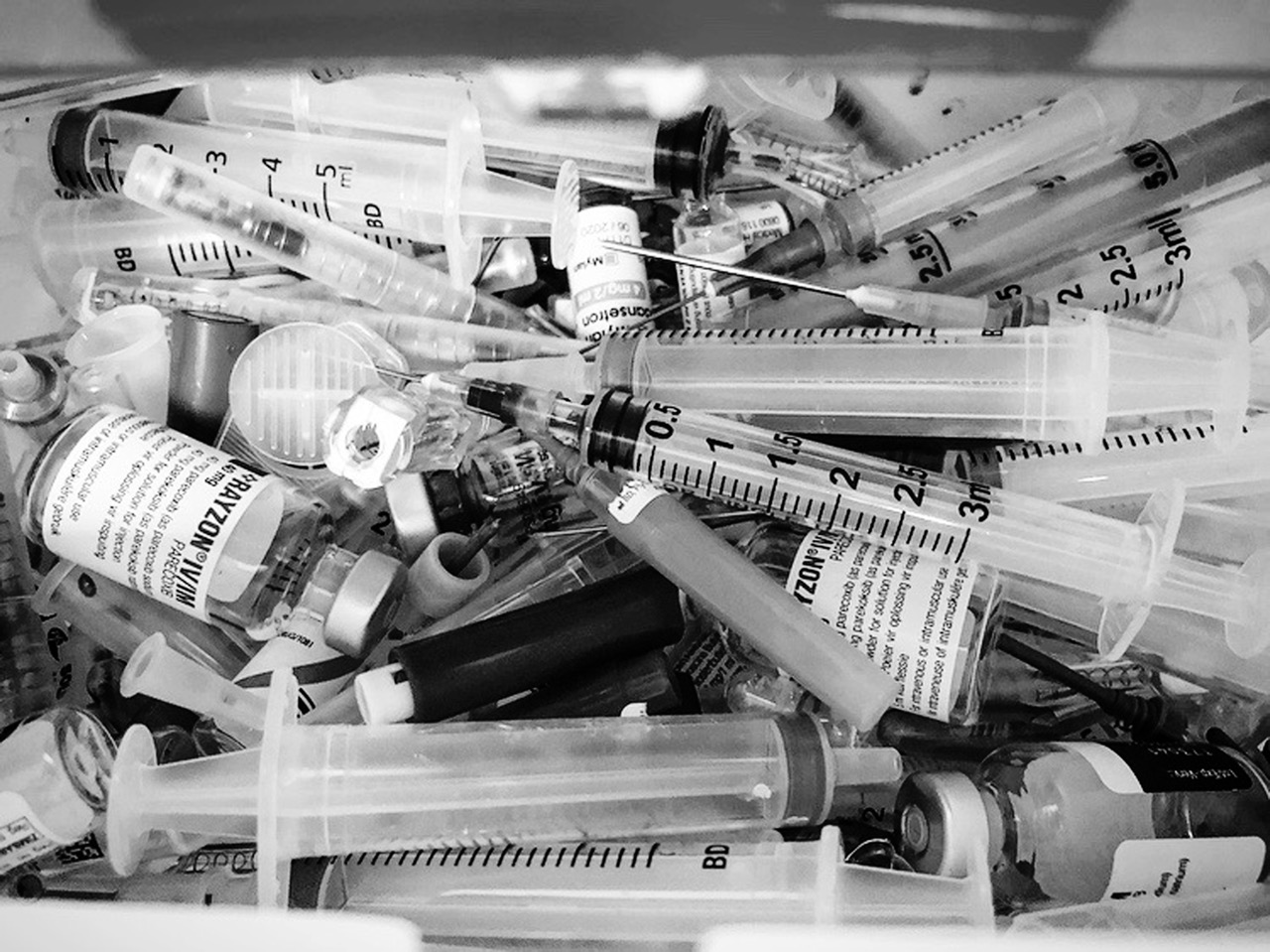 A black and white photo of a pile of syringes.