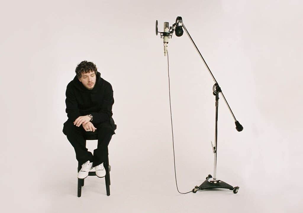 Jack Harlow sitting on a stool near a mic