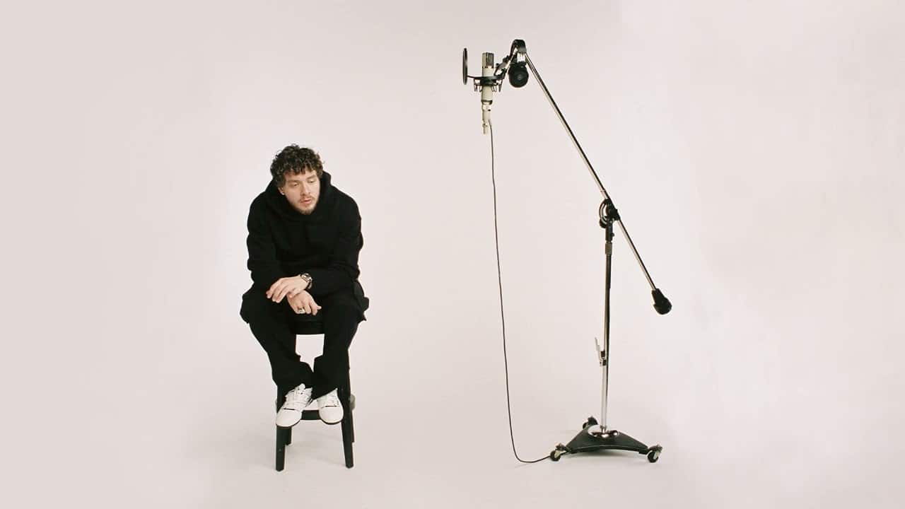 Jack Harlow sitting on a stool near a mic