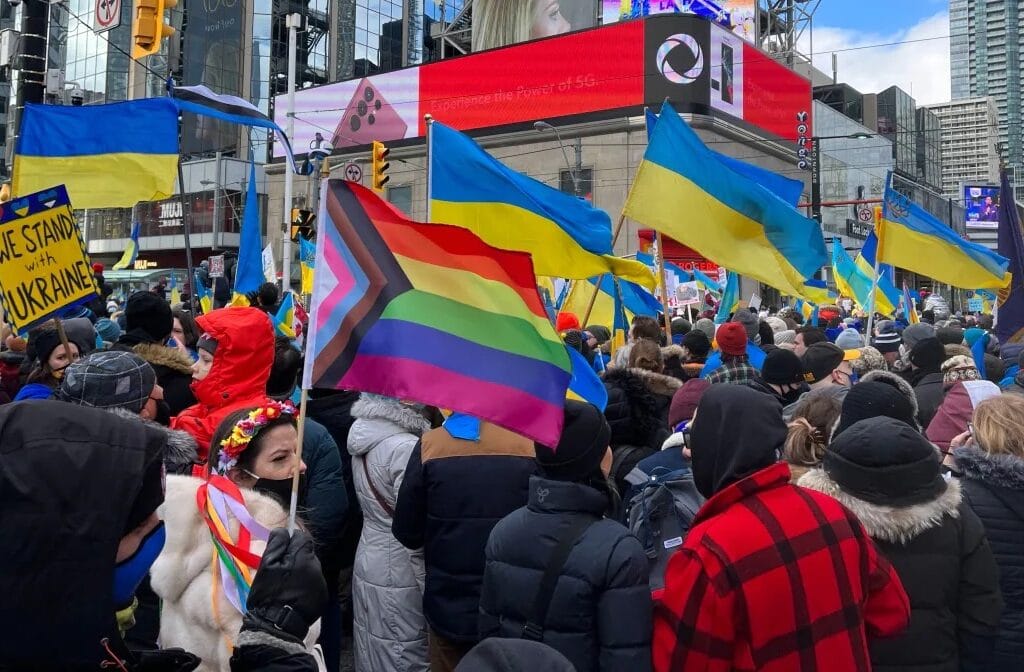 A pride flag waving amidst Ukrainian flags at a protest